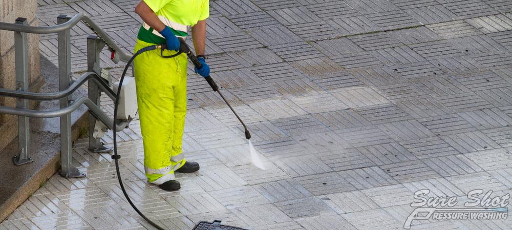 Worker,Cleaning,A,Street,Sidewalk,With,High,Pressure,Water,Jet. How To Properly Clean the Grout in Your Walkway