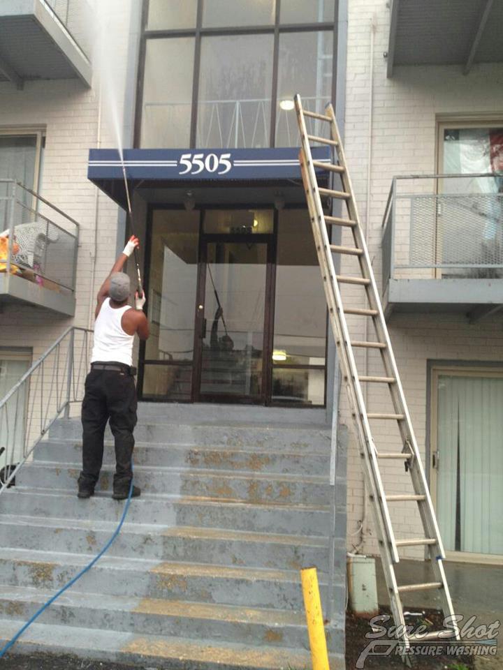 10471_494028153959378_132990905_n condo exteriors A person from a pressure washing company is power washing the entrance and stairs of a building under the sign "5505," with a ladder leaning against the facade.