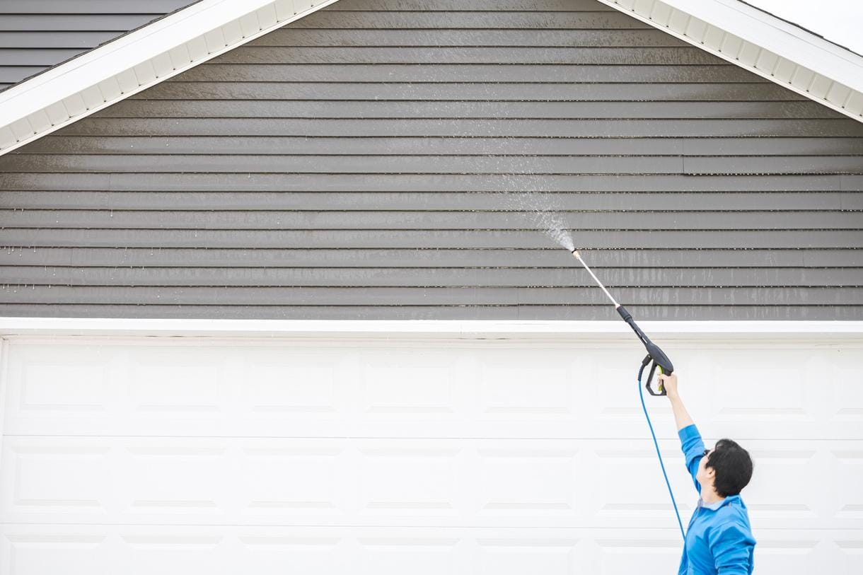 172254365681472090 (23) power wash house Person pressure washing the upper exterior wall of a garage.