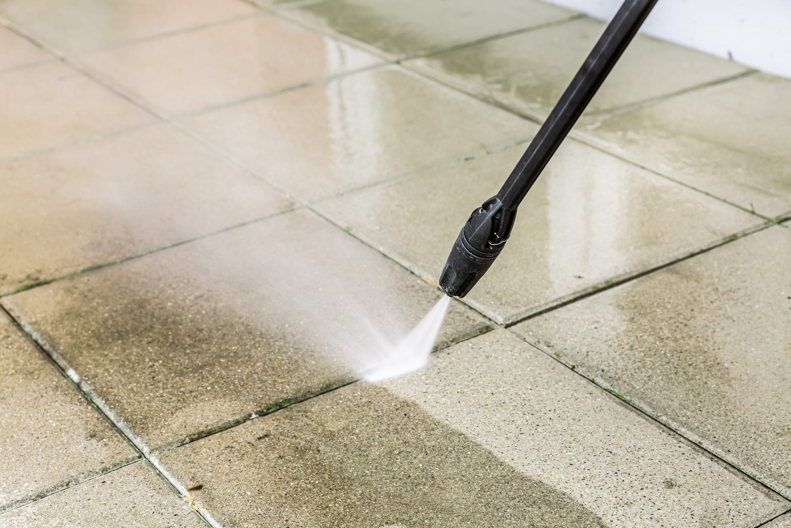 Detail of cleaning terrace with high-pressure water blaster, cleaning dirty paving stones A pressure washer cleaning dirty outdoor tiles, producing a visible spray of water.